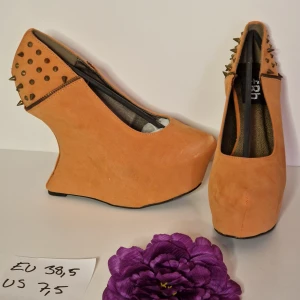 Kilklackar med nitar strl 38,5 - Häftiga kilklackar i mockaimitation med nitar. Klackhöjd ca 12cm Platå ca 3 cm Helt nya och oanvända