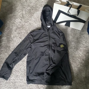 Stone Island jacka  - Riktigt snygg Stone island jacka i bra skick 9/10. En svart lätt vind jacka från Stone island! Nypris 4500kr. Passar den som är mellan 180-190 