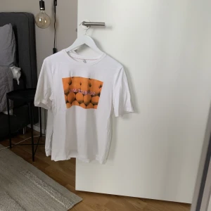 T-shirt - Vit T-shirt med orange tryck Stl M  Från Only Liten prick/fläck lite under axeln
