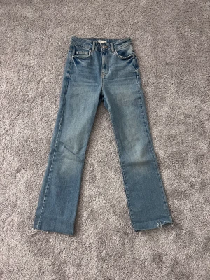 Jeans från gina tricot - Ett par blåa högmidjade jeans från gina tricot i stl 32, passar dig som är 146.
