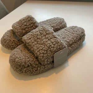 Tofflor Teddy  - Tofflor från ASOS, oanvända med lappen kvar. Står storlek M under men jag skulle säga att det är 37-38. 