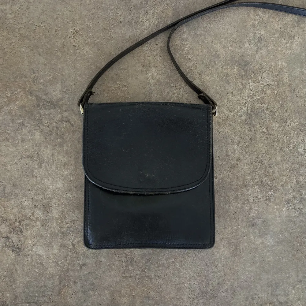 Liten svart väska i läder. Dragkedjan inuti (bild 2) är trasig men facket går att använda ändå!. Väskor.