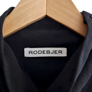 RODEBJER klänning storlek M - Klassisk klänning från Rodebjer med turtleneck, knäppning på vänster axel, 3/4 ärm och halvt transparenta detaljer.   Storlek: M  Material: Polyester  Färg: Svart  Skick: Mycket fint skick. Endast använd fåtal gånger   Mått (plant)  Längd från axelsöm: 93