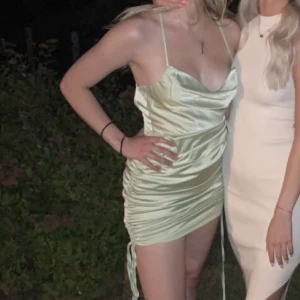 Grön justerbar silkesklänning - Grön silkesklänning som går att längdjustera med snören som sitter på sidan. Blir maxiklänning som längst och mini som kortast. Har cowlneck urringning och är i storlek XS. Använd 2 gånger.