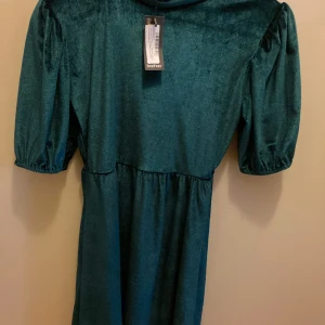 Klänning Boohoo  - En klänning från Boohoo, ganska kort och liten i storlek. Är en söt liten klänning gjord av grön sammet. Har lite puffärmar och en liten högste hals. Storlek M/40 men passar S också skulle jag tro. Helt oanvänd.