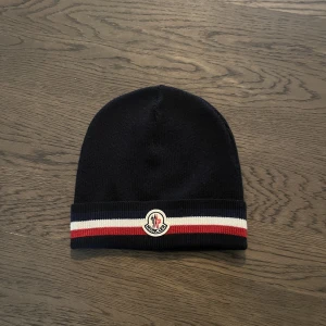 Moncler mössa - Säljer min moncler vintermössa, väldigt lite använd så den är i riktigt bra skick 8/10. Den har varit handtvättad en gång för ett par veckor sen! 