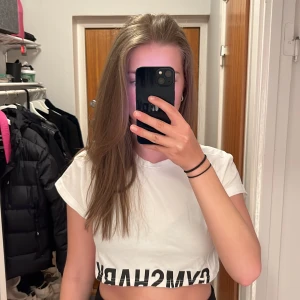 Croppad Gymshark T-Shirt - Croppad vit gymshark t-shirt. Jättefin träningströja💪 Knappt använd så nästintill nyskick🙏