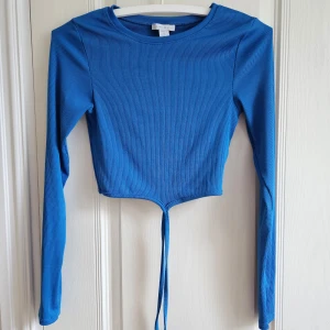 Tröja från New Yorker - Supersnygg tröja från New Yorker. Tröjan är endast provad och alltså i nyskick! Superfin klarblå färg med knytning runt magen. Storlek S