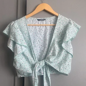 Topp - Somrig topp med knytning. Långa snören som görs att det även kan knytas ett varm runt midjan. Stl L