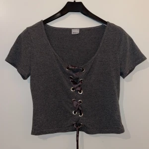 Grå t-shirt - Grå t-shirt med snörning från Gina Tricot. Storlek M.