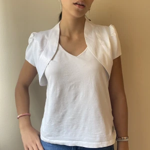 Vit bolero  - Skitsnygg vit bolero i glansigt material. Mycket bra skick! Storlek 36. Passar XS och S