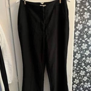 Svarta kostymbyxor  - Svarta kostymbyxor från Nelly med raka ben/vida ben. Använda men i mycket gott skick.  Storlek M/38