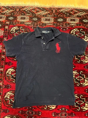 Polo Ralph Lauren Piké  - Vintage Marinblå Polo Ralph Lauren Piké. Vet inte hur gammal den är men täcken på användning finns då den bl.a. är solblekt. Tveka inte att höra av dig vid frågor eller funderingar.