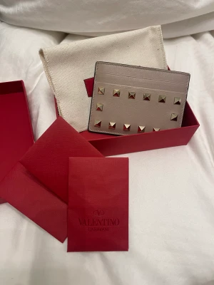 Valentino rokstud plånbok - Säljer min fina valentino rokstud plånbok. Den är använd väldigt sparsamt och har inga ytliga skador. Köptes på Valentinos egna hemsida tillkommer äktighets bevis och nitar samt boxen för plånboken. Nypris 2900. 