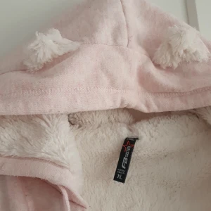 Träningsjacka  - Ljusrosa, fluffig, gosig på insidan, öron på luvan. 