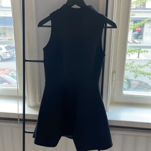 Svart klänning  - Svart kortklänning. Dragkedja i rygg och liten volang nedtill. 