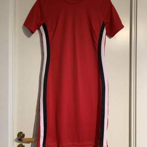 Säljer en röd klänning med vita och svarta stripes på sidorna från GinaTricot i storlek M. Nyskick - Aldrig använd, endast testad.