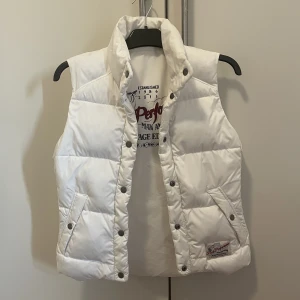 Väst - Vit vintage dunväst från Peak Performance. Den är heritage edition, vilket är en collection från 2011 då de återskapade få designs från deras första år. Den är tvåsidig, ena sidan är en helt vanlig dunväst och andra sidan matt med tryck på ryggen