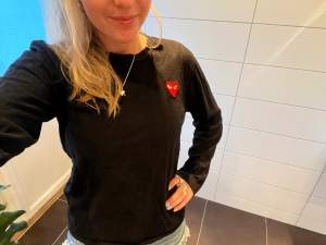 Unisex cool långärmad T shirt från CDG (Comme ses Garcons) köpt på NK i Stockholm, fint skick svart med ett rött hjärta(deras märke) på vänster bröst. Strl 36🩷