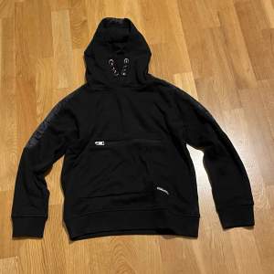 Hoodien är ifrån märket Garcia. Detta är en svart hoodie som har lite glansiga armar. Skicket på tröjan är 8/10. Storlek är 152/158. 