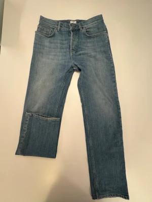 Ljusblå raka jeans från Filippa K - Säljer ett par ljusblå raka jeans från Filippa K. Klassisk femficksmodell med normalhög midja och bälteshällor. Jeansen har en snygg tvättad look och är tillverkade i mjukt denimtyg. Perfekta för en avslappnad och trendig stil.