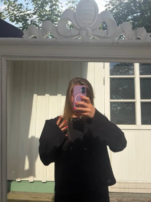 Svart oversized stickad tröja - En svart stickad tröja med oversized passform och vida ärmar. Tröjan har en enkel design utan synliga mönster eller detaljer och är perfekt för en avslappnad och trendig look.