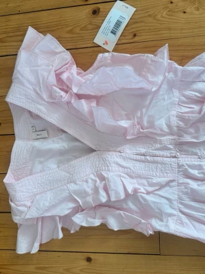 Rosa blus - Supersöt HELT NY ljusrosa blus från Nelly med volanger i strl 36!💗Passar till både jeans och kjol för en trendig stil. Säljer pga fel storlek🫶 Det är bara att skriva för fler frågor eller funderingar💗