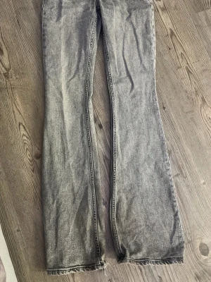 Gråa utsvängda jeans - Säljer ett par gråa jeans med utsvängda ben och råa kanter nertill. Jeansen har klassisk femficksdesign och är gjorda i denim. Perfekta för dig som gillar en avslappnad och trendig look.