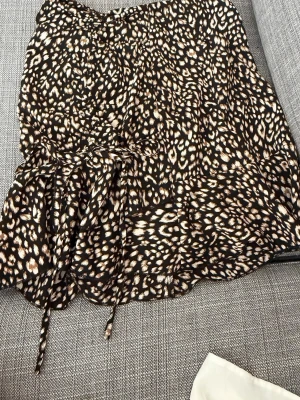 Leopard kjol - En kortare leopard kjol som passer fint till sommaren i storlek xs/S. Den har en liten knytning längst ner till vänster och en dragkedja på sidan. 