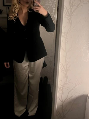 Svart figursydd kavaj från Bik Bok - Snygg svart kavaj från Bik Bok med figurnära passform och två knappar framtill. Klassisk modell med långa ärmar och diskreta fickor. Perfekt att styla till både jeans och kostymbyxor för en clean look.