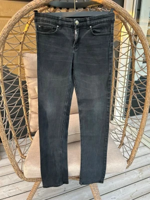 Svarta skinny jeans med slitningar - Svarta skinny jeans med klassisk femficksmodell. Jeansen har dragkedjegylf och silverfärgad knapp.