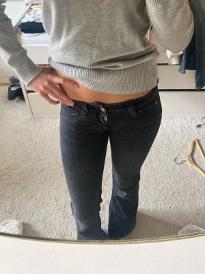 Svarta bootcut jeans med låg midja - Snygga svarta jeans med låg midja och bootcut passform. Jeansen har klassisk femficksdesign och gylf med knapp. Perfekta för dig som gillar en trendig och avslappnad stil.