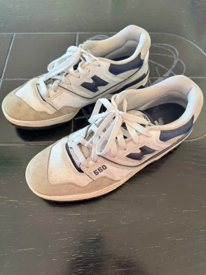 New Balance 550 vita och blå sneakers - Säljer ett par New Balance 550 sneakers i vitt och marinblått. Köpta från farfetch, storlek 40,5 