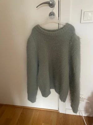 Ljusgrön fluffig stickad tröja - Supermysig ljusgrön stickad tröja med fluffig känsla. Tröjan har rund halsringning och långa och puffiga ärmar. Den har ull i sig så den är väldigt varmt. Passar dig som gillar en enkel men trendig look. Använd endast fåtal gånger!!😇