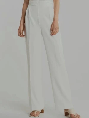 Vit halterneck jumpsuit - Snygg vit jumpsuit med halterneck och vida ben. Överdelen har korsad design och markerad midja med rynkdetaljer. Tillverkad i ett mjukt, lätt tyg som ger en elegant siluett. Perfekt för dig som vill sticka ut med en stilren och modern look.