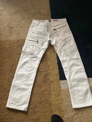 Vita jeans med dragkedjor och detaljer - !!passar både storlek S och M!!Säljer ett par vita jeans med flera dragkedjor, fickor och coola sömnadsdetaljer. Jeansen har raka ben. !!!Pris går att diskuteras!!!