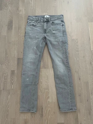 Gråa jeans med slitningar - Ett par gråa jeans med slitningar i modellen slimmy. Jeansen är i bra skick och är i storlek W31 L32. Priset kan diskuteras vid en snabb affär!