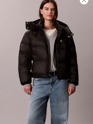 Svart vinterjacka Calvin Klein  - Snygg svart pufferjacka med hög krage och avtagbar huva. Jackan har en diskret logga på bröstet, dragkedja framtill och breda kanaler för extra värme. Perfekt för kalla vinterdagar och ger en cool, avslappnad look. Använd fåtal gånger. 