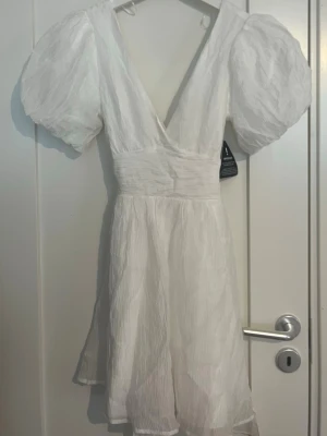 Vit studentklänning - Vit studentklänning från Gina Tricot 2025. Aldrig använd och prislapp finns kvar. Lånad sista bild för att visa hur den sitter på, klänningen har en knytning i ryggen.