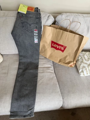 Grå Levi's 511 Slim jeans - Snygga grå Levi's 511 Slim jeans med klassisk femficksdesign och raka ben. Jeansen har en diskret tvättad look, Levi's ikoniska läderpatch bak och röd logotagg på bakfickan. Tillverkade i stretchig bomullsblandning för extra komfort. Säljes pga fel storlek och köpt i annan stad! 