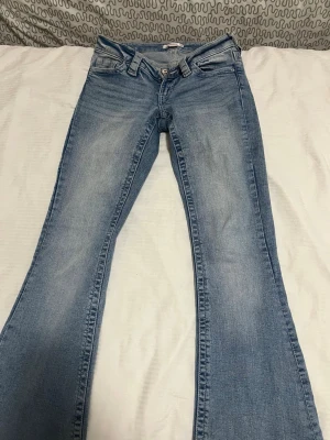 Ljusblå bootcut jeans från Gina Tricot - Säljer ett par ljusblå bootcut jeans från Gina Tricot. Tagit dem till en professionell så att de kan sy dem till kortare så passar folk som är 150-156cm!Jeansen har klassisk femficksdesign, låg midja och utsvängda ben. 