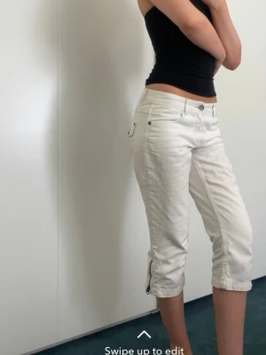Vita capri shorts med dragkedja - Snygga vita capri shorts med låg midja och dragkedja vid benslut. Klassisk femficksmodell, perfekta för sommaren. Passar dig som gillar en avslappnad och stilren look.