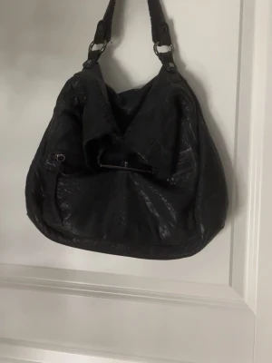 Svart handväska i skinn - Säljer en svart, mjuk och rymlig handväska från Zara woman som inte säljs mer🫶🏻 den är i skinn med bred axelrem och dragkedjeficka framtill. Väskan har en avslappnad slouchy form och silverfärgade metalldetaljer. Perfekt för dig som vill ha plats för allt du behöver under dagen. Skriv om du har några frågor💕