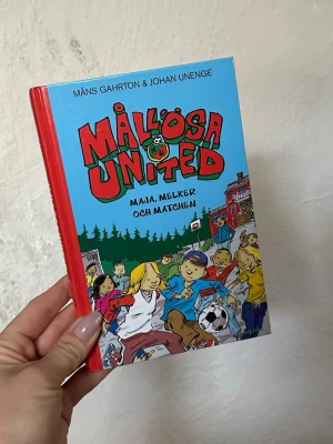 Mållösa United: Maja, Melker och matchen - En färgglad barnbok med hårda pärmar, skriven av Måns Gahrton och Johan Unenge. Omslaget är blått och rött med tecknade figurer som spelar fotboll. Boken handlar om fotboll, vänskap och livet i småstaden Mållösa.