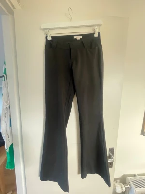 Svarta utsvängda kostymbyxor Gina Tricot - Säljer ett par svarta kostymbyxor från Gina Tricot i storlek XS. Byxorna har utsvängda ben och hög midja, vilket ger en snygg siluett. Perfekta till en trendig och stilren look. Materialet känns mjukt och följsamt.
