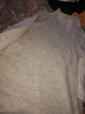 Beige stickad polotröja - Mysig beige stickad polotröja med lång ärm och rak passform. Tröjan har en hög krage och är tillverkad i ett mjukt material som passar perfekt för kyligare dagar. Enkel och stilren design som är lätt att matcha med olika outfits.