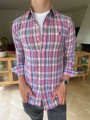 Ralph Lauren skjorta slim fit rutig rosa herr - Klassisk långärmad skjorta från Polo Ralph Lauren i modellen Slim Fit. Storlek S/P (Small). Rosa rutig i hög kvalitet och i mycket fint skick utan skavanker. Perfekt till både vardag och fest.Sökord: herrskjorta märkeskläder ralph lauren skjorta slimfit rutig rosa#poloralphlauren #ralphlauren #slimfit #vintageralphlauren #herrskjorta #ralphlaurensmall #rutigskjorta. Pyttelite missfärgning på innersidan av kragen. Inget man tänker på.