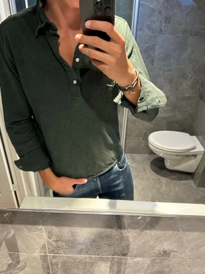 Mörkgrön långärmad piké  - Snygg mörkgrön långärmad piké från John Henric. Riktigt bra skick på den och inga defekter. Jag på bilden är 188cm och bör strlk M. Hör av er vid fler frågor;)
