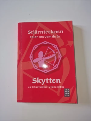 Stjärntecken Skytten bok - En röd bok med titeln 'Stjärntecknen talar om vem du är: Skytten'. Boken handlar om stjärntecknet Skytten och dess egenskaper, med datum ca 22 november–21 december. Utgiven av ICA Bokförlag. Perfekt för dig som vill veta mer om astrologi och personlig utveckling.