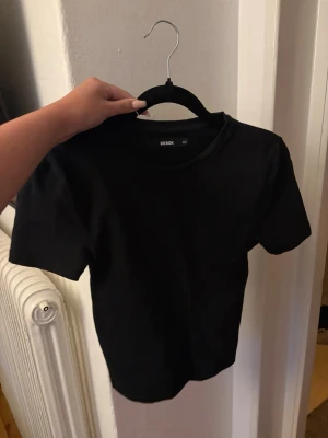 Svart basic t-shirt - En enkel svart t-shirt med rund hals och korta ärmar.  Perfekt att matcha med jeans eller kjol för en clean och stilren look.